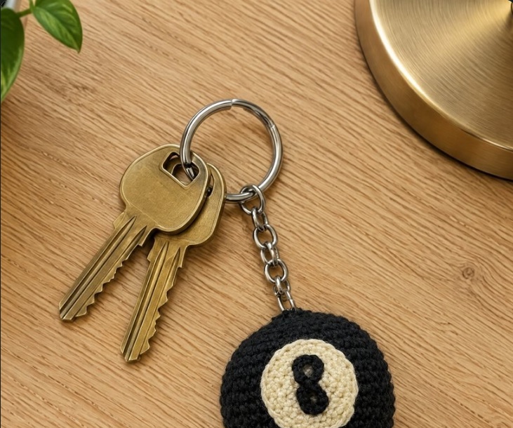 Lucky the 8-Ball key ring with brass keys on a wooden table